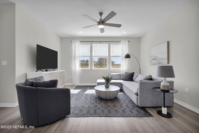 living room featuring wood finished floors, a ceiling fan, and baseboards