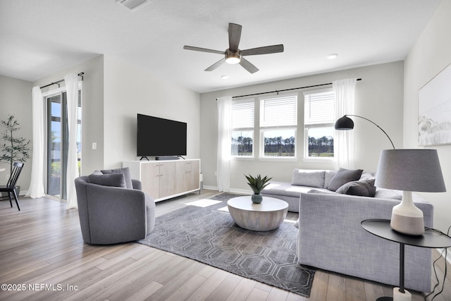 living room featuring visible vents, ceiling fan, baseboards, and wood finished floors