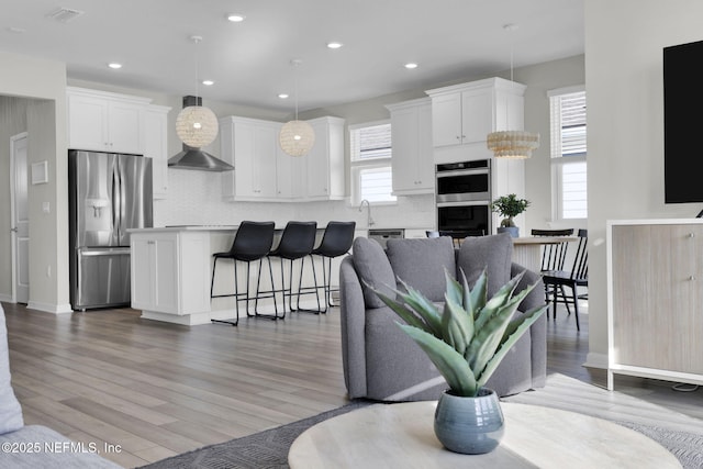 living area with recessed lighting, a healthy amount of sunlight, and wood finished floors