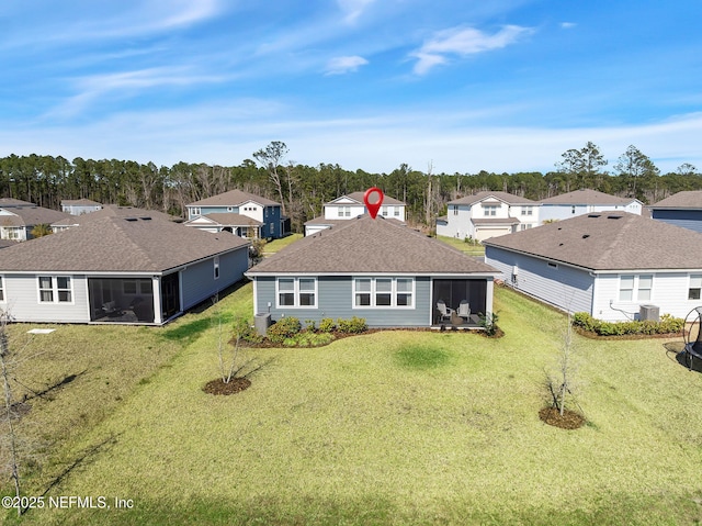 rear view of property featuring a yard, a residential view, a sunroom, and central air condition unit