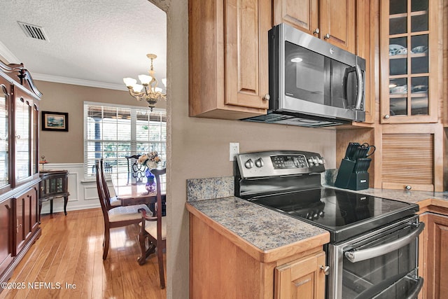 kitchen featuring appliances with stainless steel finishes, light hardwood / wood-style flooring, a textured ceiling, a chandelier, and crown molding