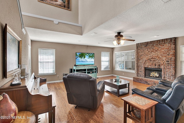 living room featuring light hardwood / wood-style floors, a wealth of natural light, a textured ceiling, and a fireplace