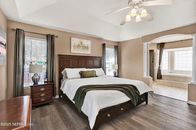 bedroom featuring hardwood / wood-style floors, a textured ceiling, decorative columns, and a raised ceiling