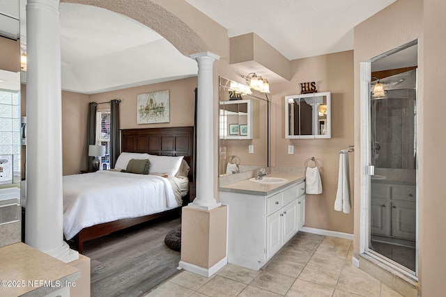 bedroom with light tile patterned floors, sink, decorative columns, and a textured ceiling