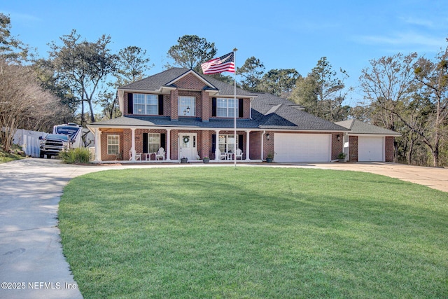 view of front of home with covered porch, a garage, and a front yard