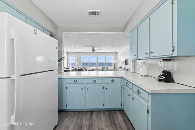 kitchen with visible vents, open floor plan, freestanding refrigerator, blue cabinets, and light countertops