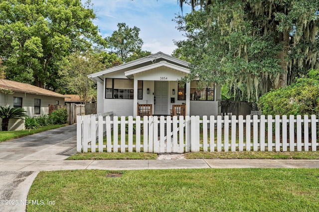 bungalow-style home featuring a porch, a fenced front yard, and a front lawn