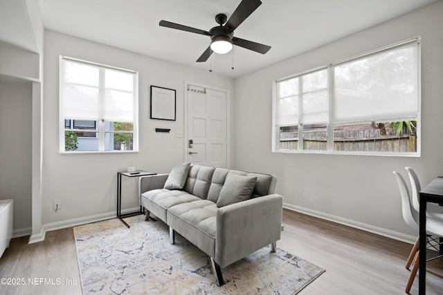 sitting room featuring ceiling fan, light wood-style flooring, and baseboards