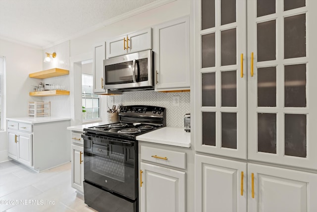 kitchen featuring black range with electric cooktop, white cabinetry, light countertops, backsplash, and stainless steel microwave