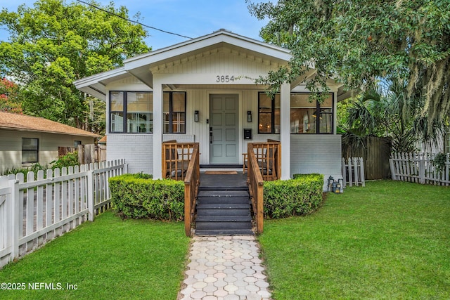 view of front facade featuring a sunroom, a front lawn, fence private yard, and brick siding