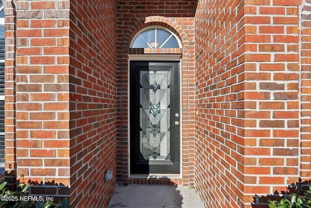 entrance to property featuring brick siding