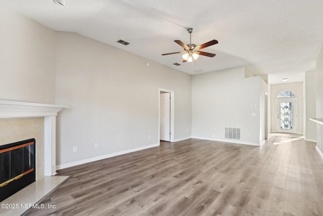 unfurnished living room with wood finished floors, a fireplace, visible vents, and baseboards