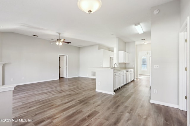 unfurnished living room featuring a sink, visible vents, wood finished floors, and a ceiling fan