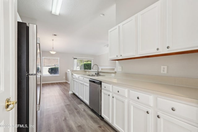 kitchen with white cabinets, stainless steel appliances, light wood-style flooring, and a sink