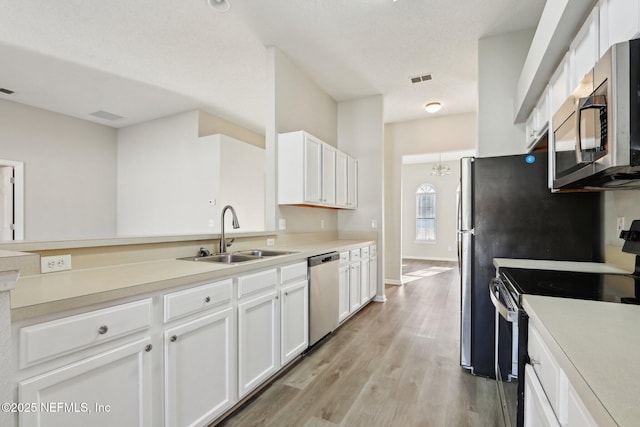 kitchen with visible vents, a sink, light wood-style floors, appliances with stainless steel finishes, and white cabinets