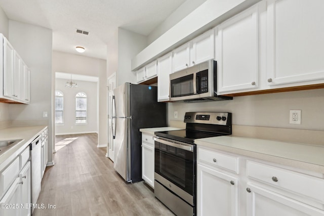 kitchen featuring visible vents, light wood-style flooring, appliances with stainless steel finishes, white cabinets, and light countertops