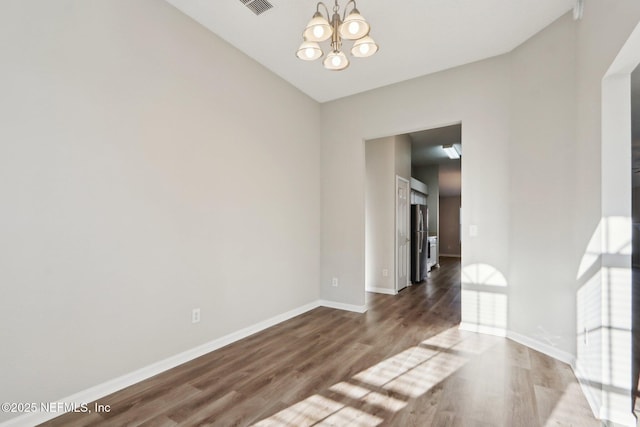 unfurnished room featuring visible vents, baseboards, an inviting chandelier, and wood finished floors