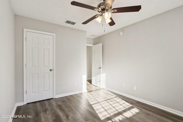 unfurnished bedroom featuring visible vents, a textured ceiling, baseboards, and wood finished floors