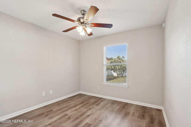 empty room featuring ceiling fan, baseboards, and wood finished floors