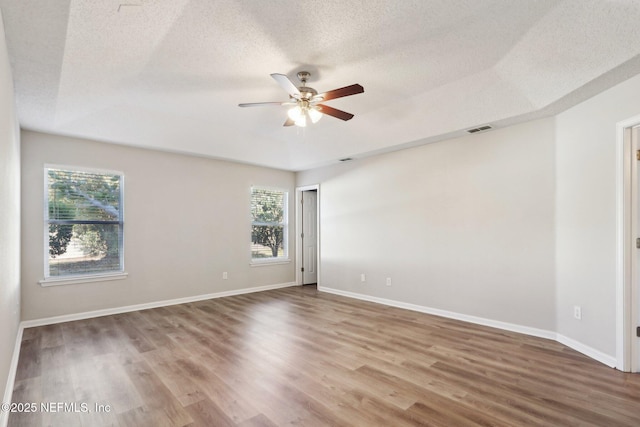 unfurnished room with visible vents, a textured ceiling, baseboards, and wood finished floors