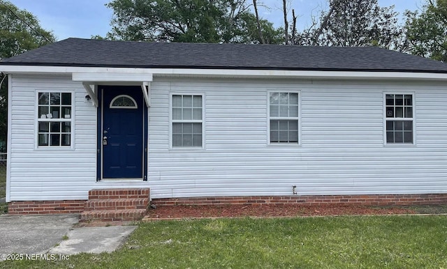 view of front facade with a shingled roof, entry steps, and a front lawn