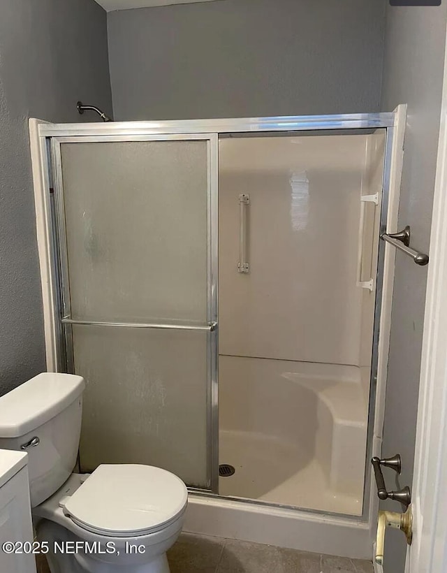 bathroom featuring vanity, toilet, a shower with shower door, and tile patterned floors