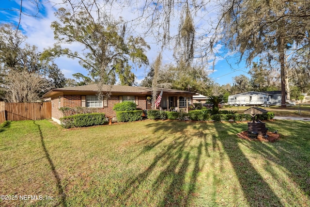 view of front of property with brick siding, fence, and a front lawn