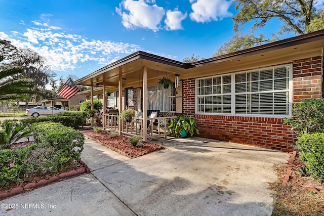 property entrance with brick siding and a porch