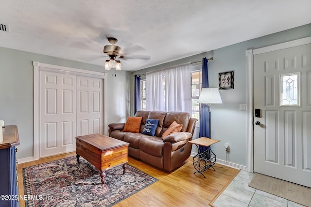 living area featuring a ceiling fan, visible vents, and baseboards