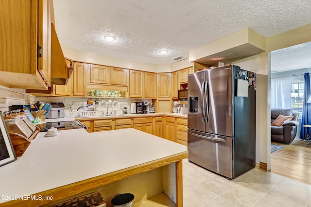 kitchen with light brown cabinets, visible vents, light countertops, stainless steel refrigerator with ice dispenser, and decorative backsplash