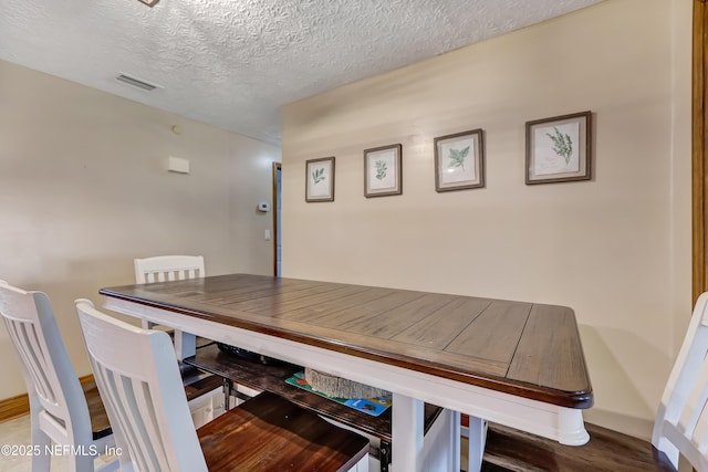 dining area featuring visible vents and a textured ceiling