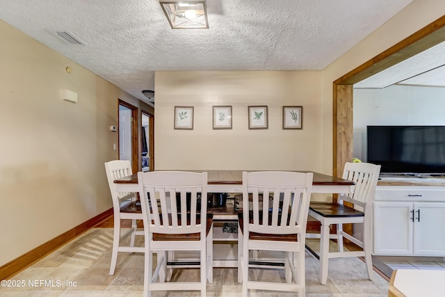 dining space featuring baseboards, visible vents, and a textured ceiling