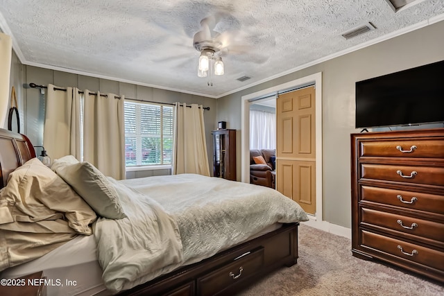 carpeted bedroom featuring ceiling fan, a textured ceiling, visible vents, and crown molding