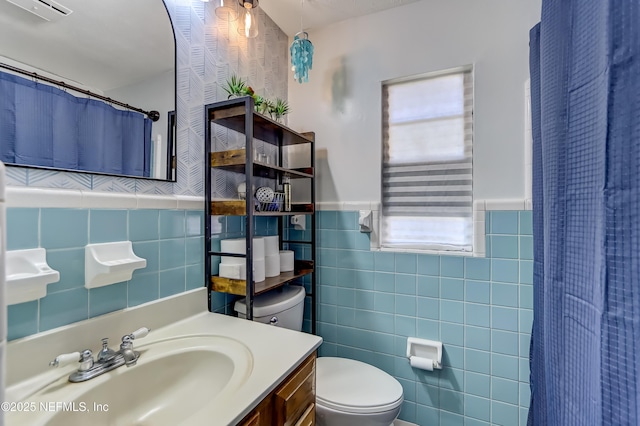 bathroom with toilet, a wainscoted wall, vanity, tile walls, and a shower with curtain