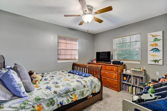 carpeted bedroom featuring multiple windows, a ceiling fan, and a textured ceiling