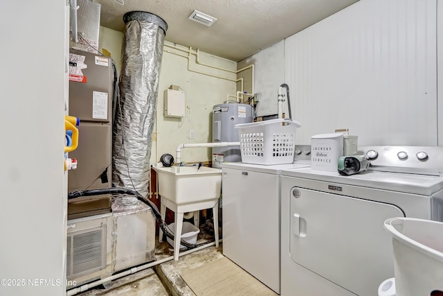 laundry room featuring laundry area, visible vents, electric water heater, washer and dryer, and a sink