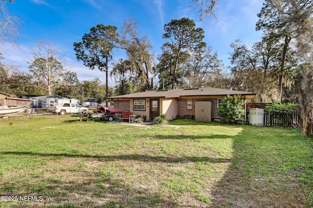 rear view of property with a yard, brick siding, and fence