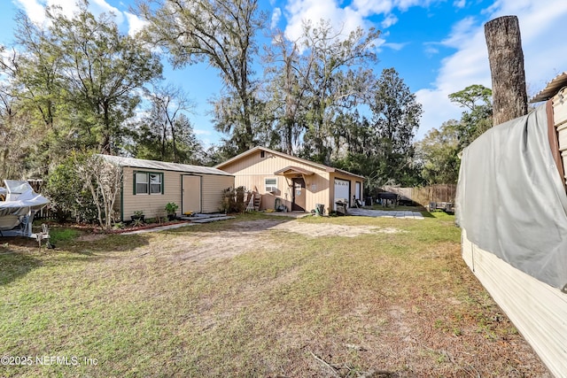 back of property featuring a yard, an outdoor structure, and fence