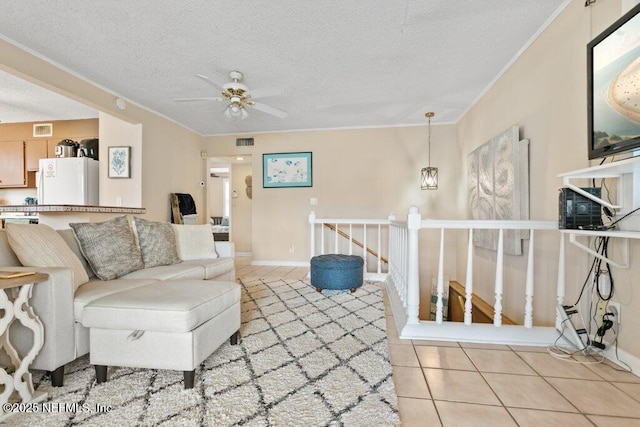 living area with ceiling fan, visible vents, a textured ceiling, and light tile patterned flooring