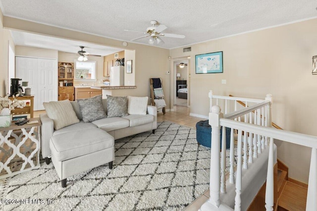 living area with baseboards, visible vents, crown molding, a textured ceiling, and light tile patterned flooring