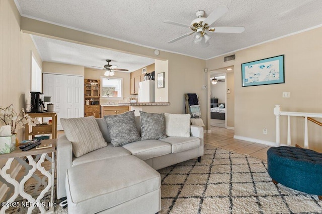 living area with ornamental molding, light tile patterned flooring, visible vents, and a textured ceiling