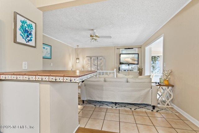 unfurnished living room featuring light tile patterned floors, a textured ceiling, a ceiling fan, baseboards, and crown molding