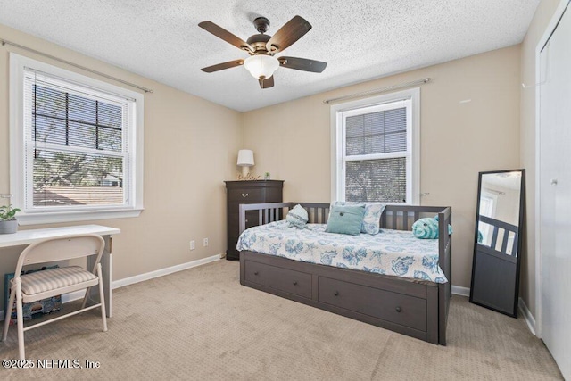 bedroom featuring light colored carpet, ceiling fan, a textured ceiling, and baseboards