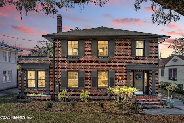 colonial home with a chimney and brick siding