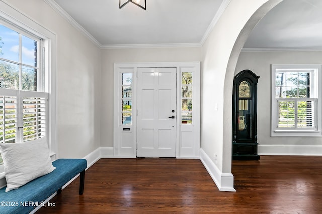 entrance foyer with dark wood-type flooring, arched walkways, ornamental molding, and baseboards