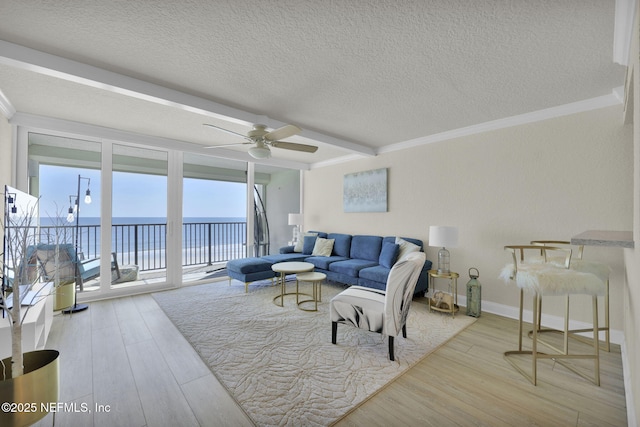 living room featuring a water view, a ceiling fan, wood finished floors, a textured ceiling, and crown molding