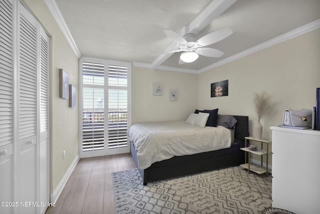 bedroom with crown molding, wood finished floors, baseboards, a closet, and ceiling fan