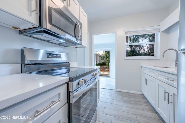 kitchen with light countertops, appliances with stainless steel finishes, and white cabinetry