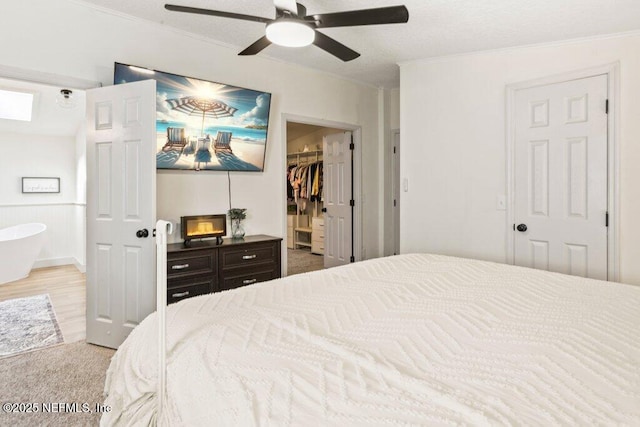 bedroom with a ceiling fan, a spacious closet, ornamental molding, and a closet