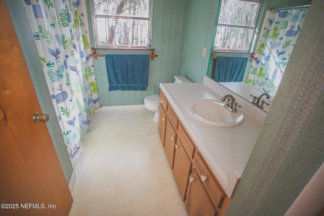 full bath with tile patterned floors, toilet, vanity, baseboards, and wallpapered walls